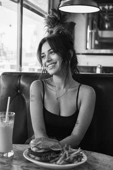 A black and white photo capturing a cheerful girl sitting in a Los Angeles restaurant booth.