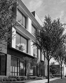 Black and white photo of a modern educational building exterior with trees in the foreground.