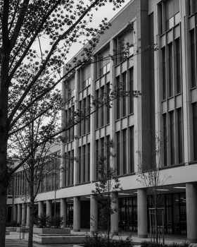 Black and white photo of a modern educational building exterior with trees in the foreground.
