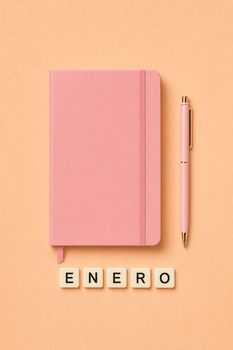 Minimalist flat lay of a pink notebook, pen, and ENERO tiles on a peach background.
