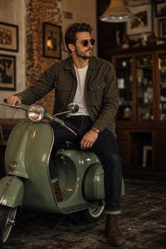 Stylish man posing on a vintage scooter indoors with retro decor.