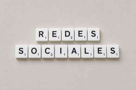White Scrabble tiles arranged to spell 'Redes Sociales' on a plain background.